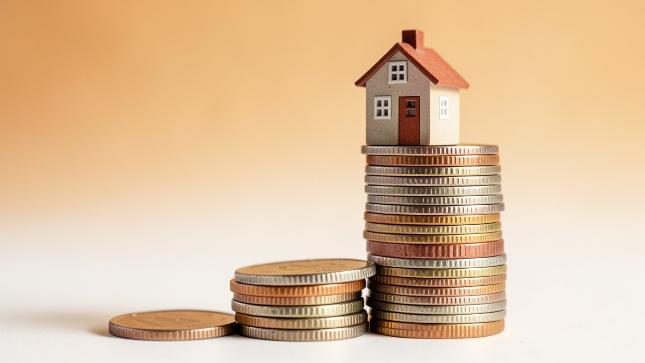 A stack of coins with a small house model on top, the stack grows from left to right.